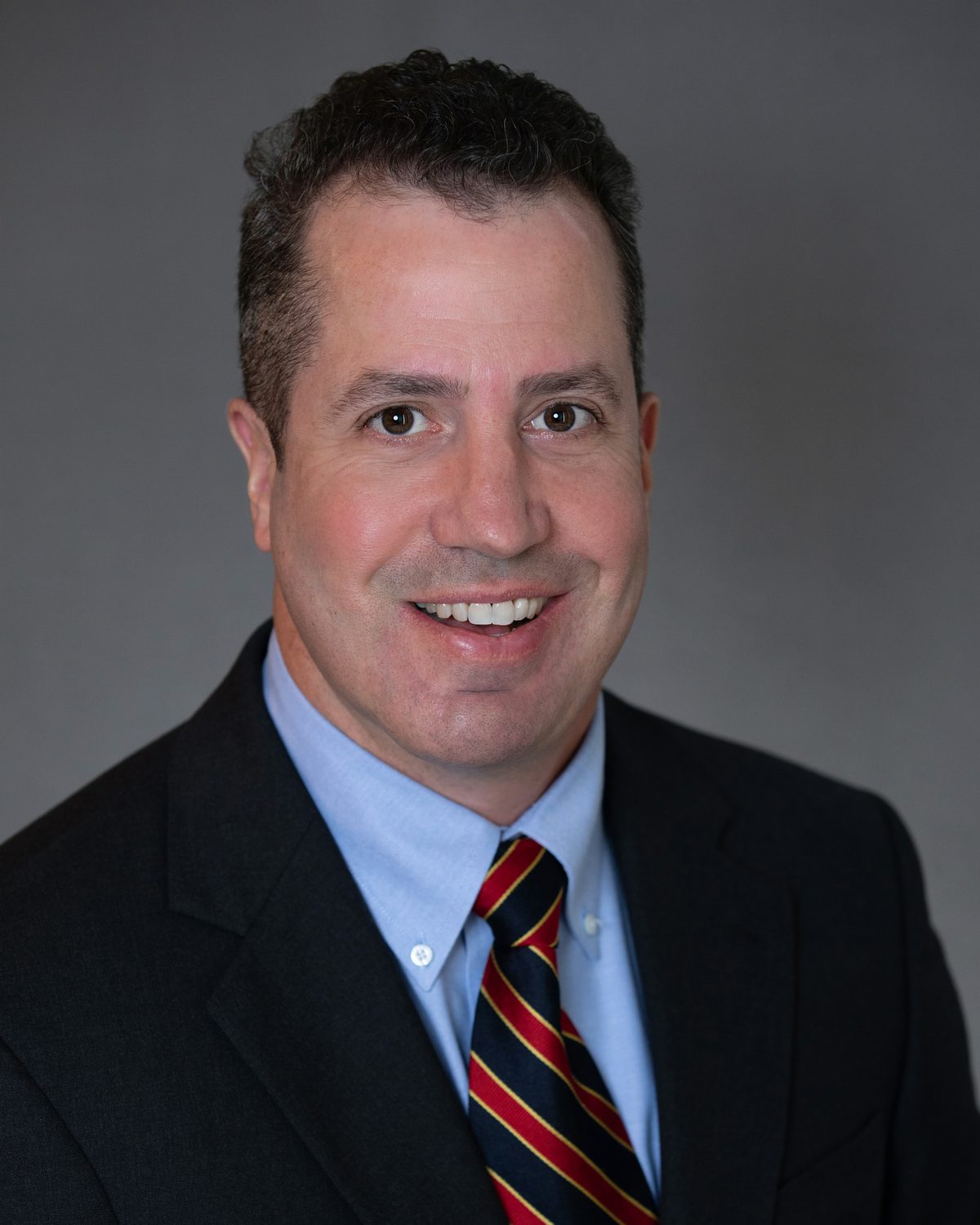 Personal injury attorney David Russo smiling in a navy suit with a red and gold striped tie